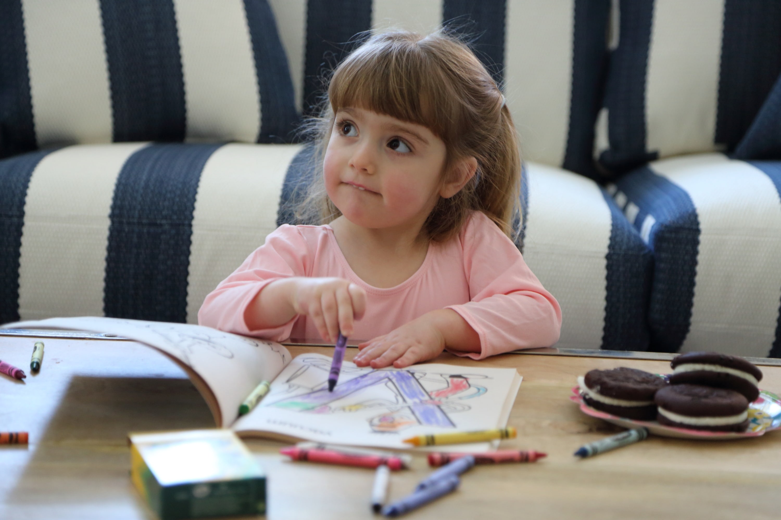child coloring in coloring book on coffee table in front of a blue and white stripped couch