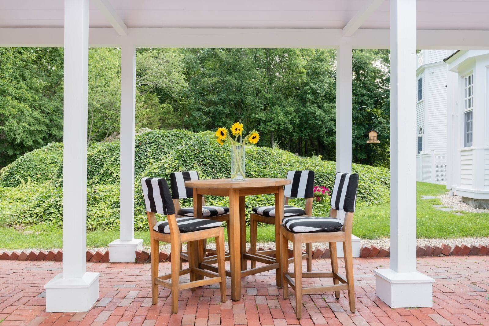 wooden hightop table and chairs under covered porch